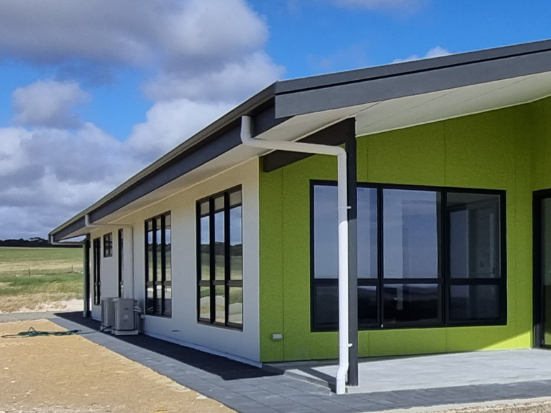 External shot of white and green custom built home