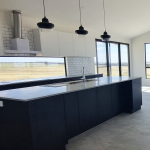 Modern dark grey kitchen with pendulum lights and stainless steel extractor