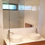 Double sink and vanity featuring waterfall shower and glass shower screen